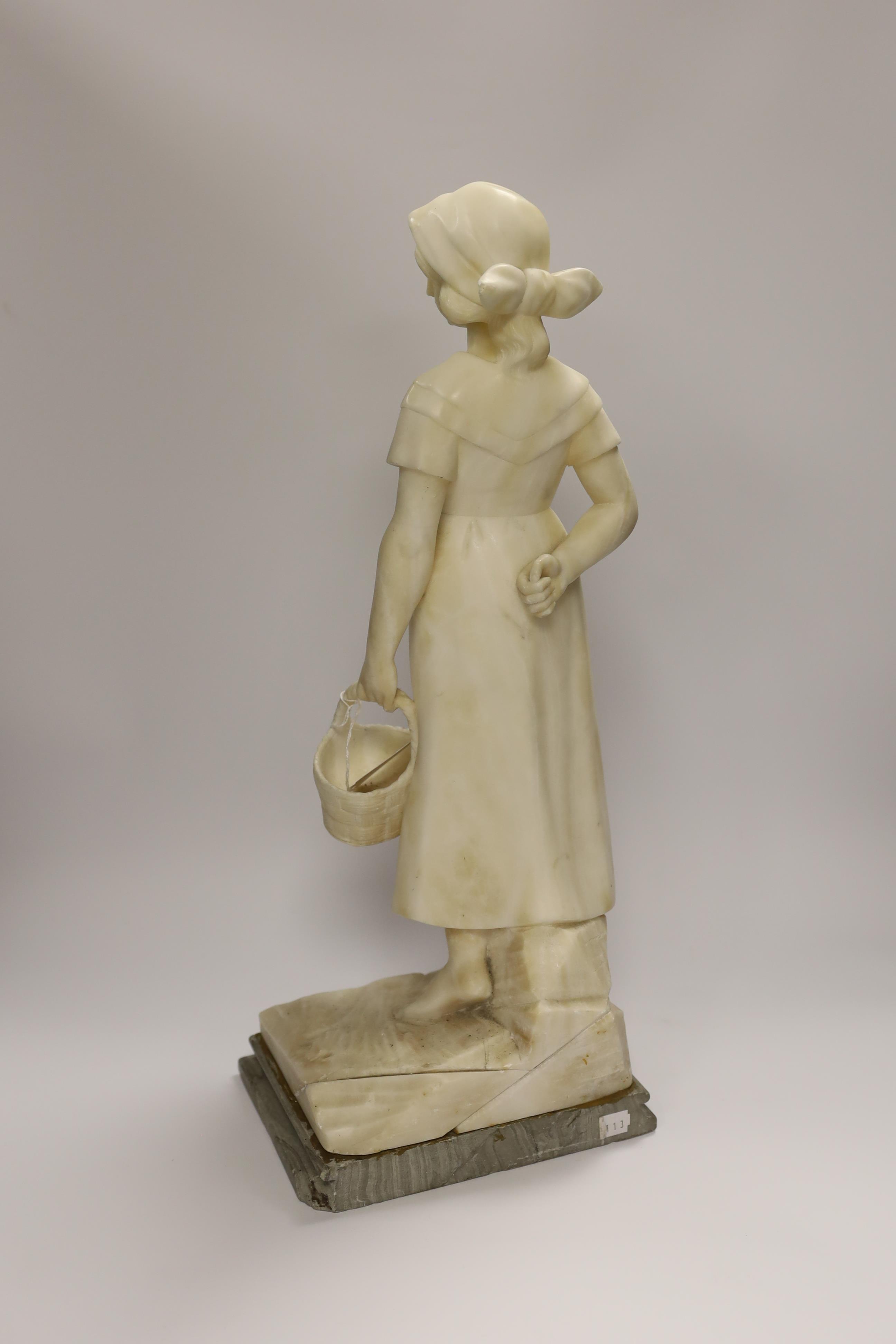 An early 20th century alabaster carved figure of a girl holding a basket, 51cm high